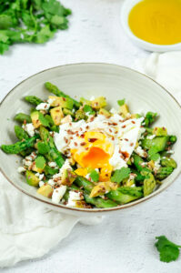 Salade dans son bol avec de l'huile d'olive et de la coriandre à côté.