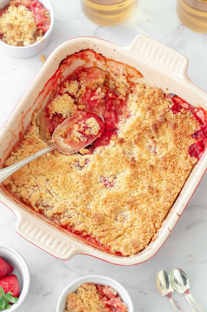 Crumble fraises et rhubarbe dans un plat avec du thé et des fraises en bol.