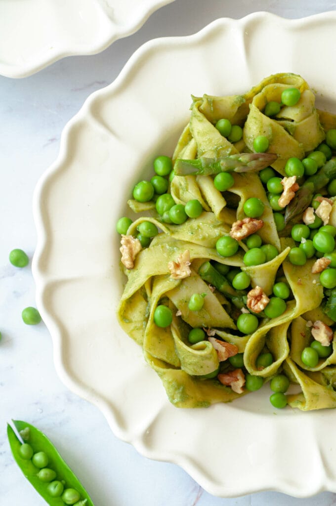 Pasta on a plate with a pea pod