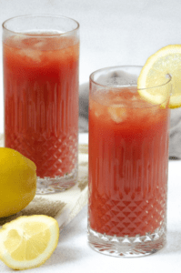 Deux verres de bloody mary avec des rondelles de citron et une tomate.