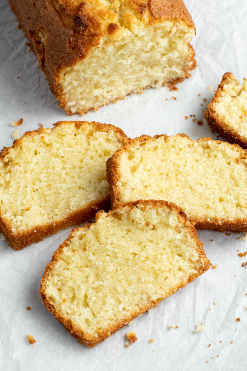 Pound cake with four slices cut off, on parchment paper.