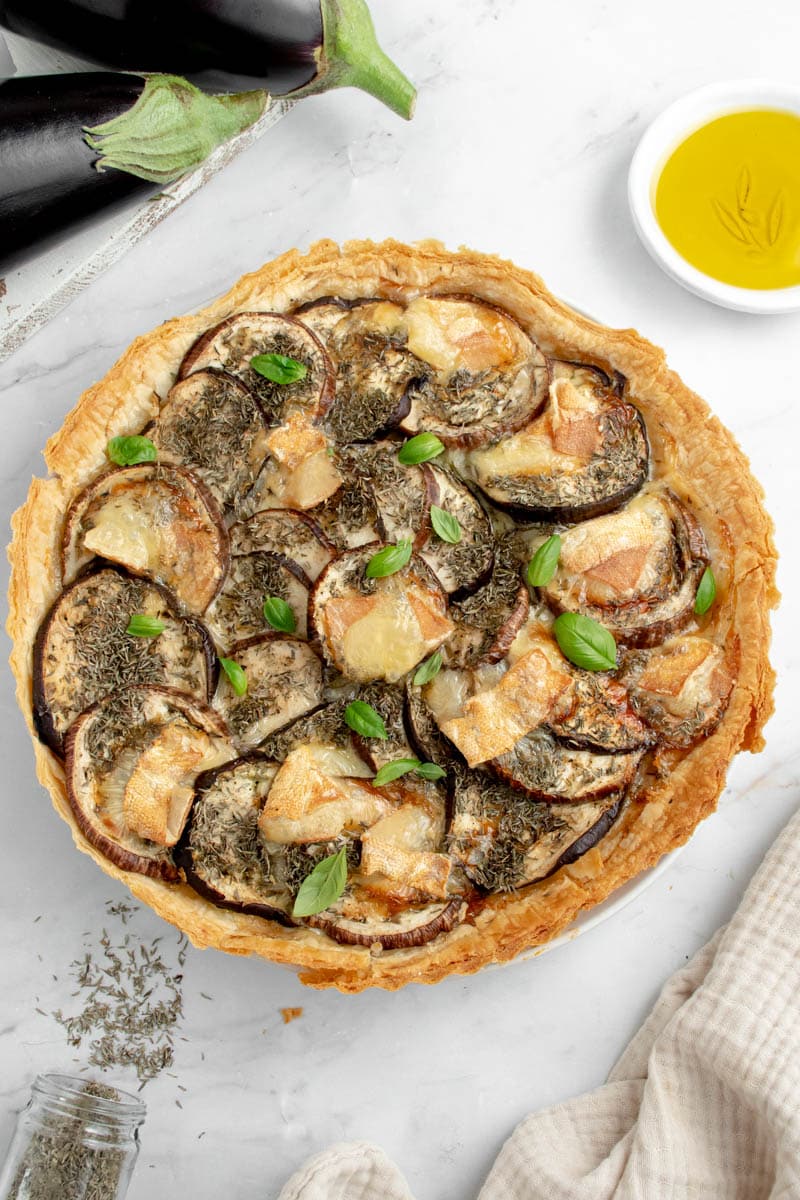 Eggplant and cheese tart in a dish with basil leaves.