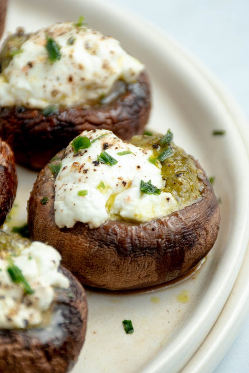 Mushrooms stuffed with goat cheese and pesto on a plate.