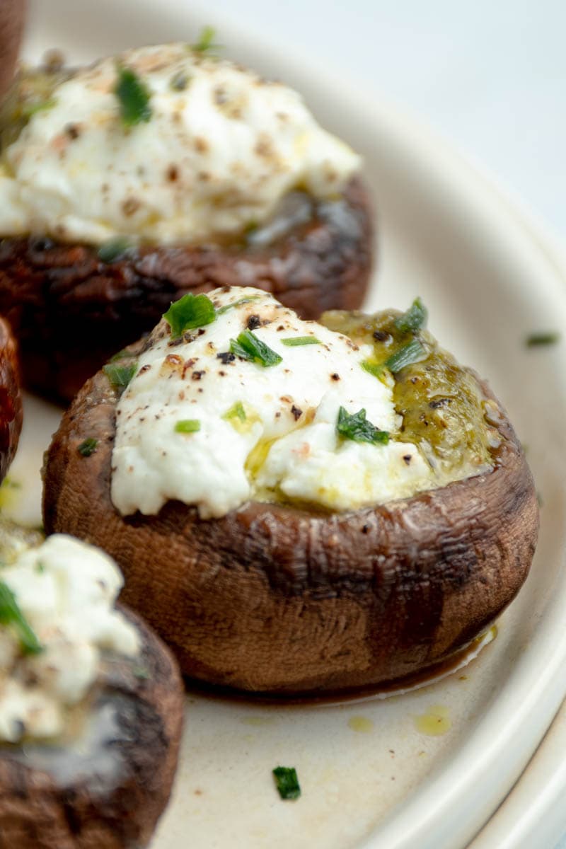 Mushrooms stuffed with goat cheese and pesto on a plate.