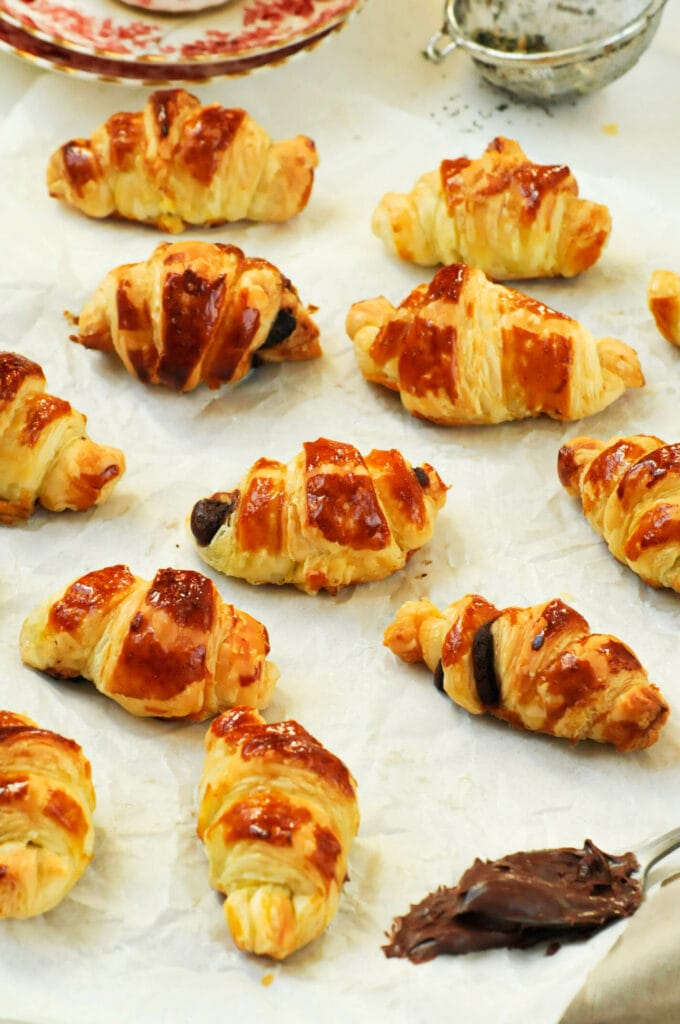 Petits feuilletés à la Nocciolata étalés sur une feuille de cuisson avec une cuillère de chocolat.