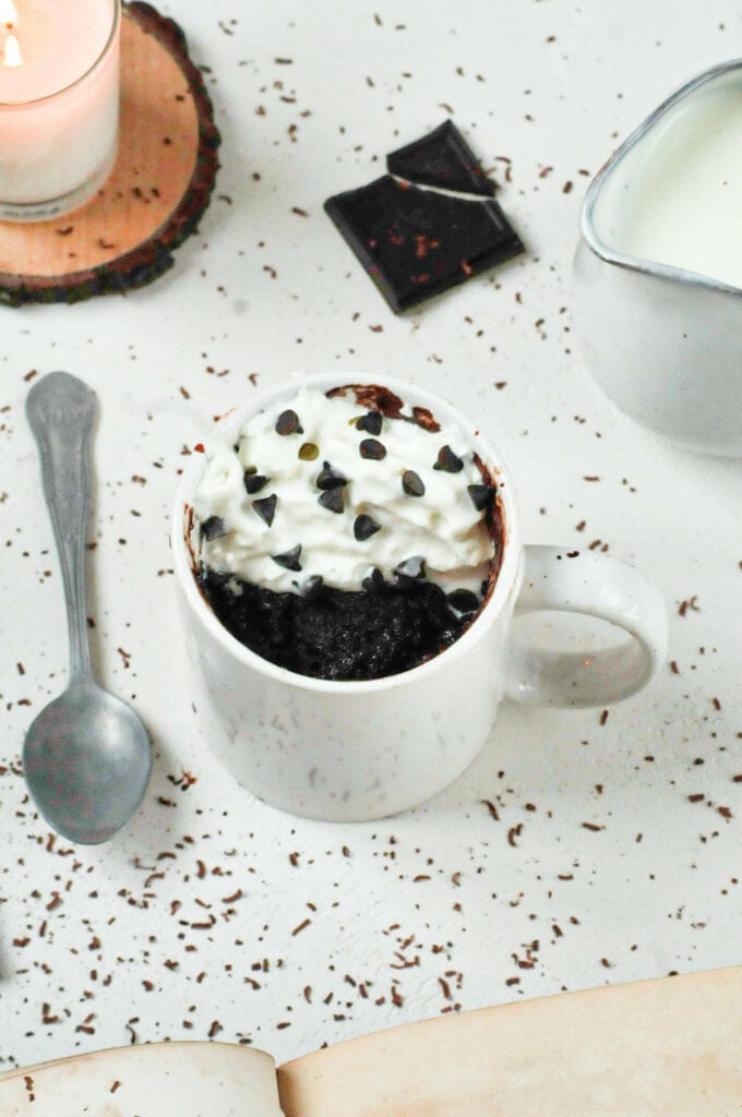 Mug cake avec un carré de chocolat et recouvert de chantilly.