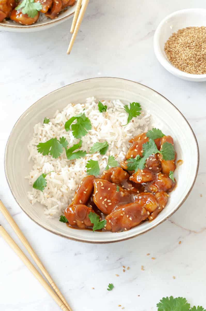 Teriyaki chicken in a bowl with rice and cilantro.