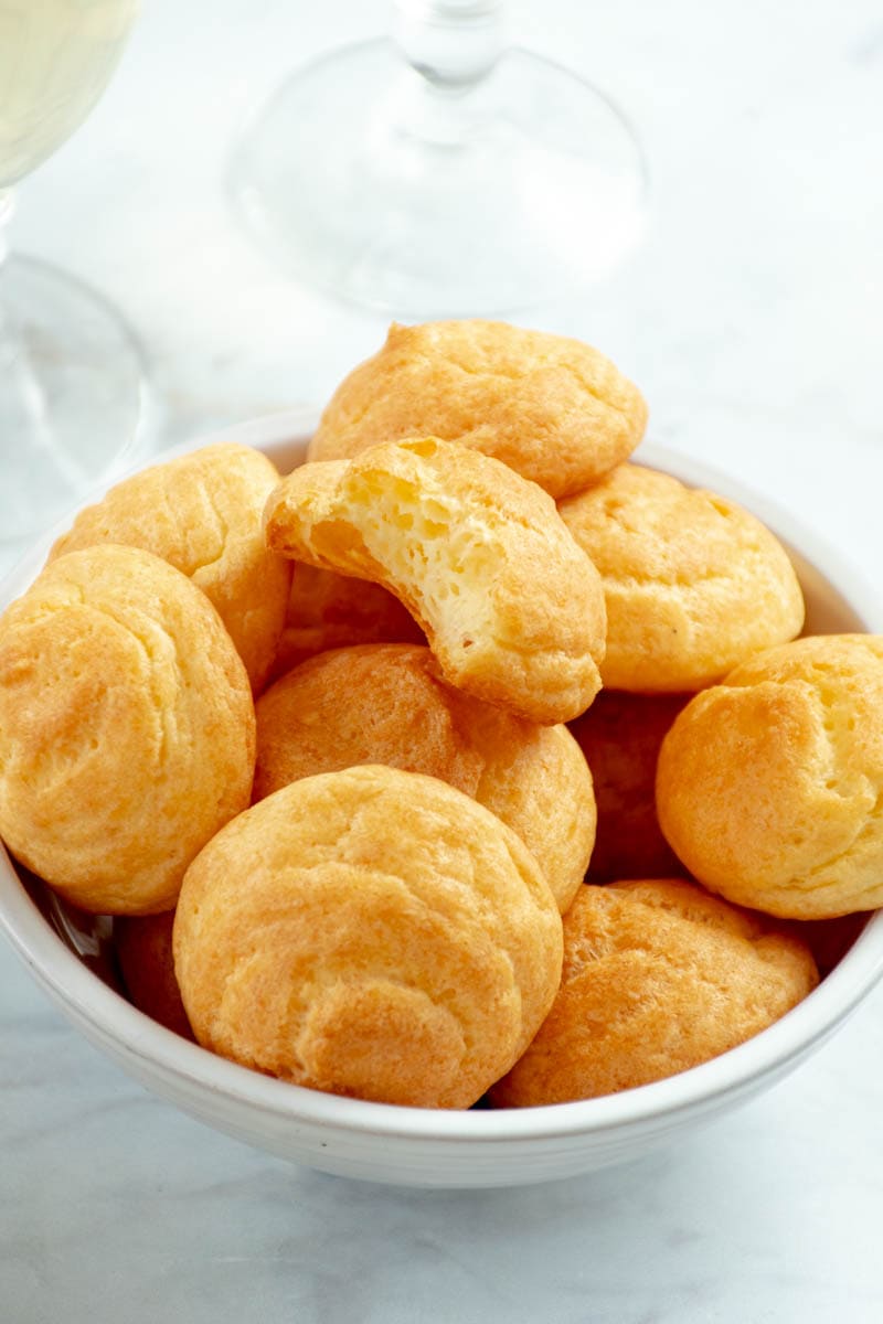Cheese gougère crunched and placed on a pile of gougères.