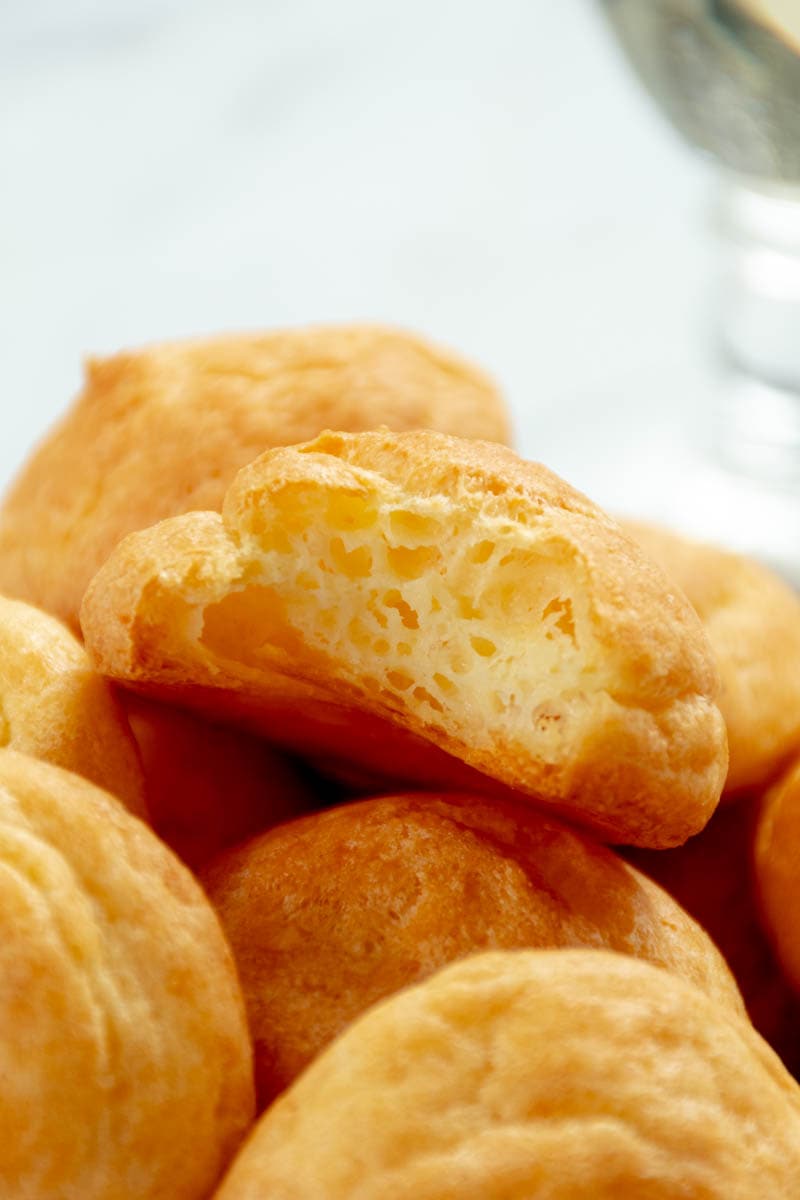 Cheese gougère crunched and placed on a pile of gougères.