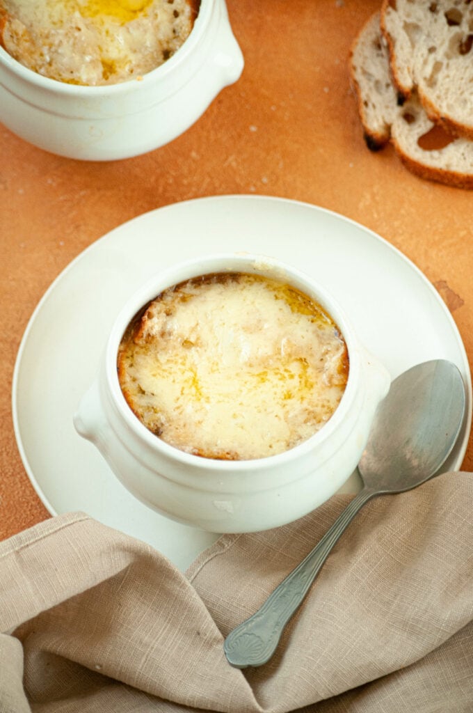 Soupe à l'oignon dans un bol sur une assiette avec une cuillère et une serviette.