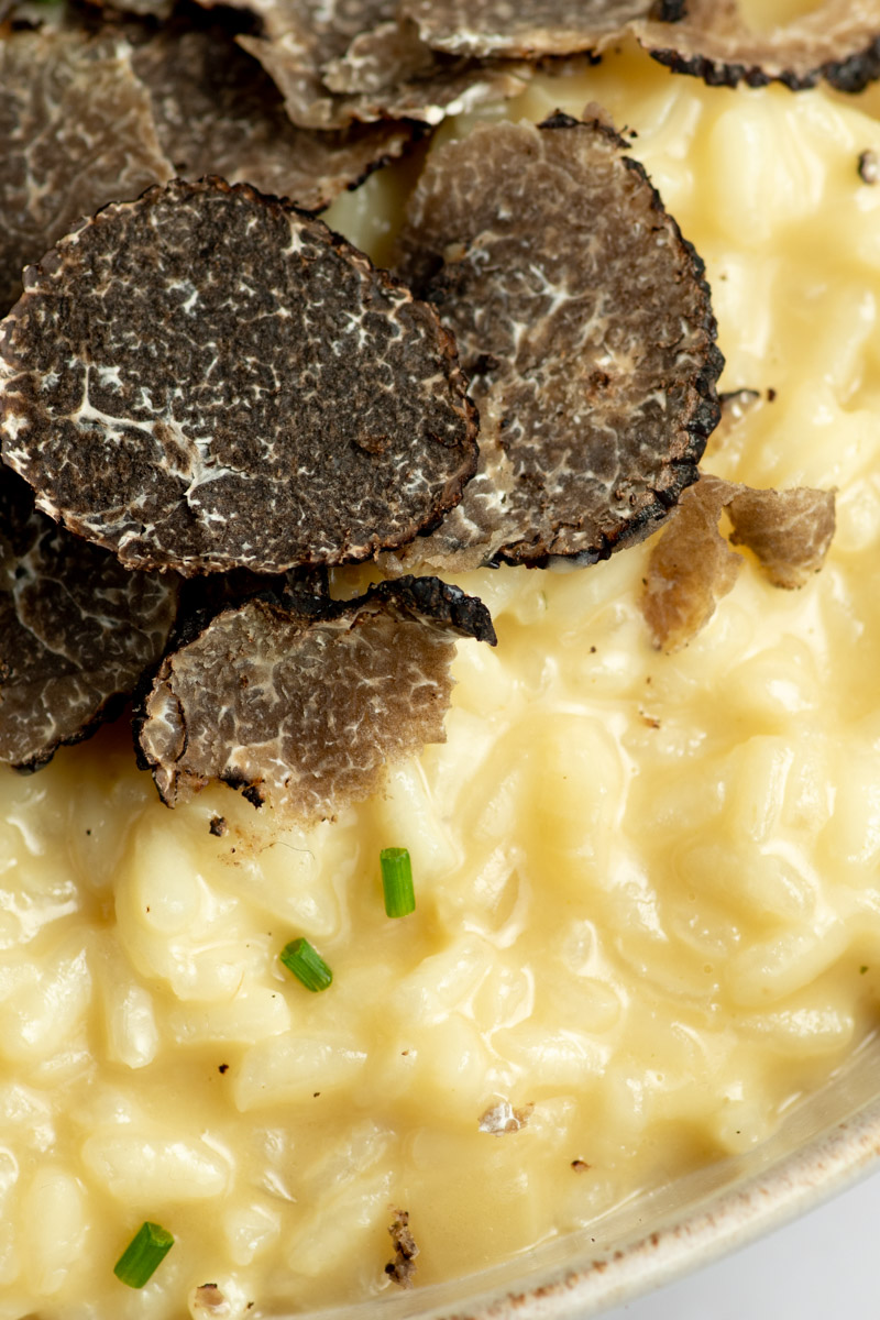 Black truffle risotto in a beige bowl.