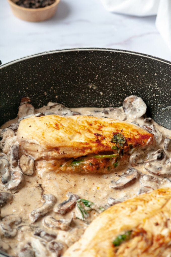 Escalopes de poulet fourrées dans une poêle avec sauce aux champignons.