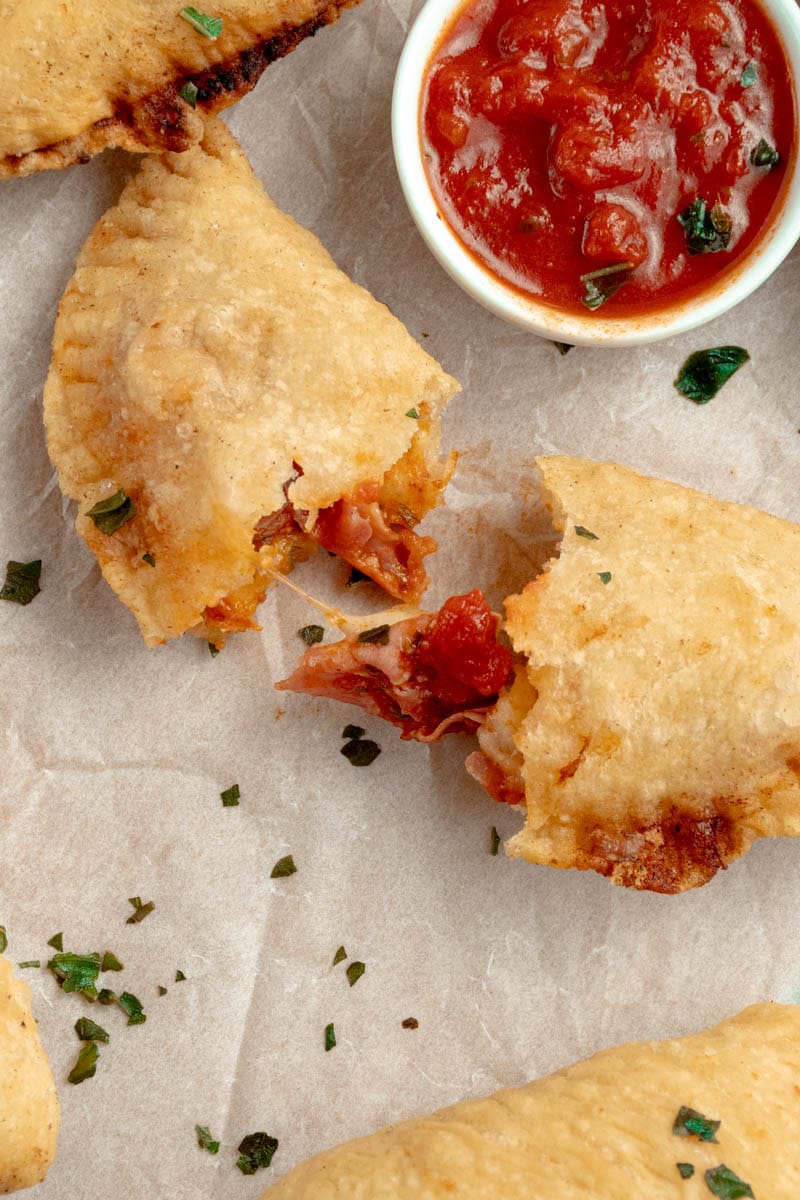 Panzerotti cut in half with a string of cheese sticking out.
