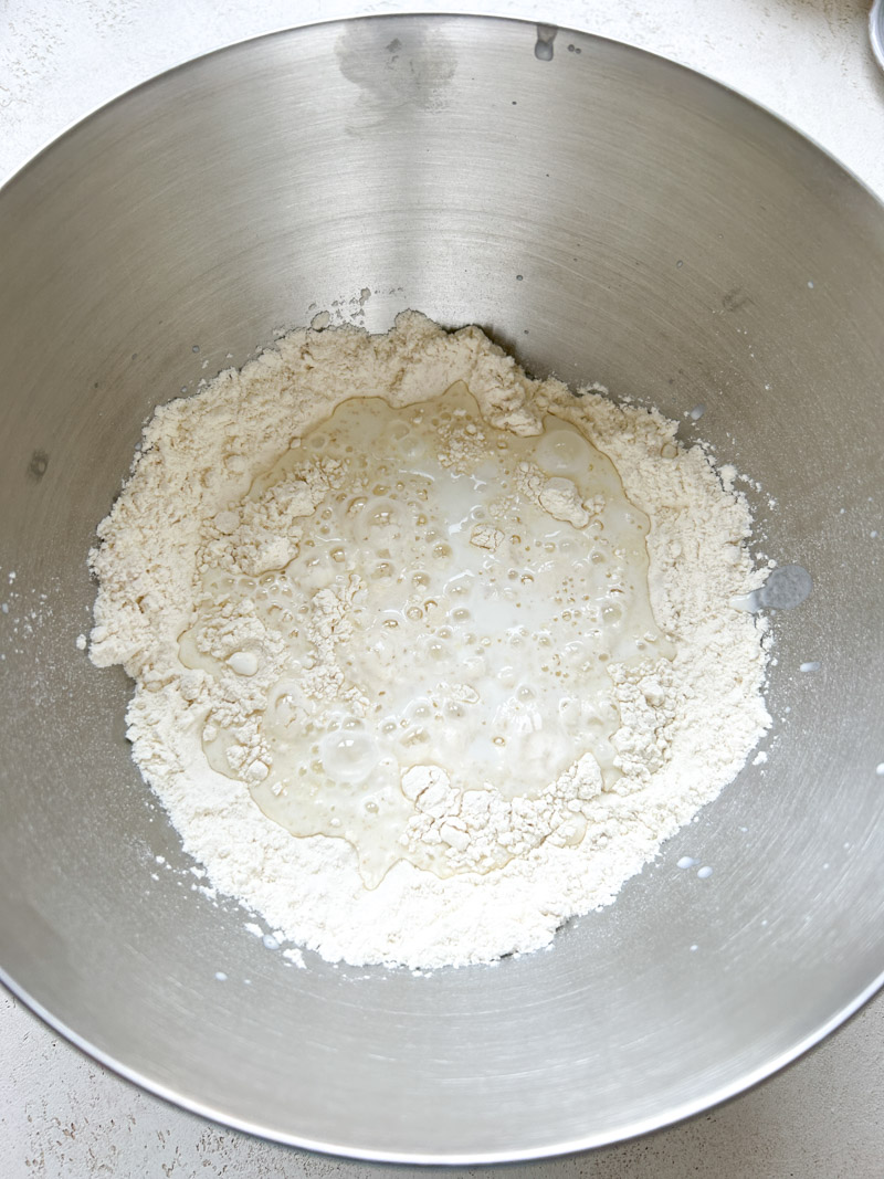 Farine et mélange d'eau et de yaourt dans le grand bol en inox.