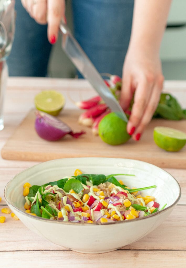 Salade et personne qui coupe un citron vert en arrière-plan.