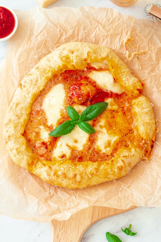 Pizza Margherita avec des bords fourrés à la mozzarella sur une planche.