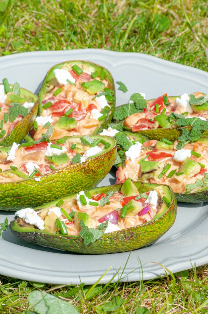 Avocado shells stuffed with salmon, goat's cheese and tomato on a plate.