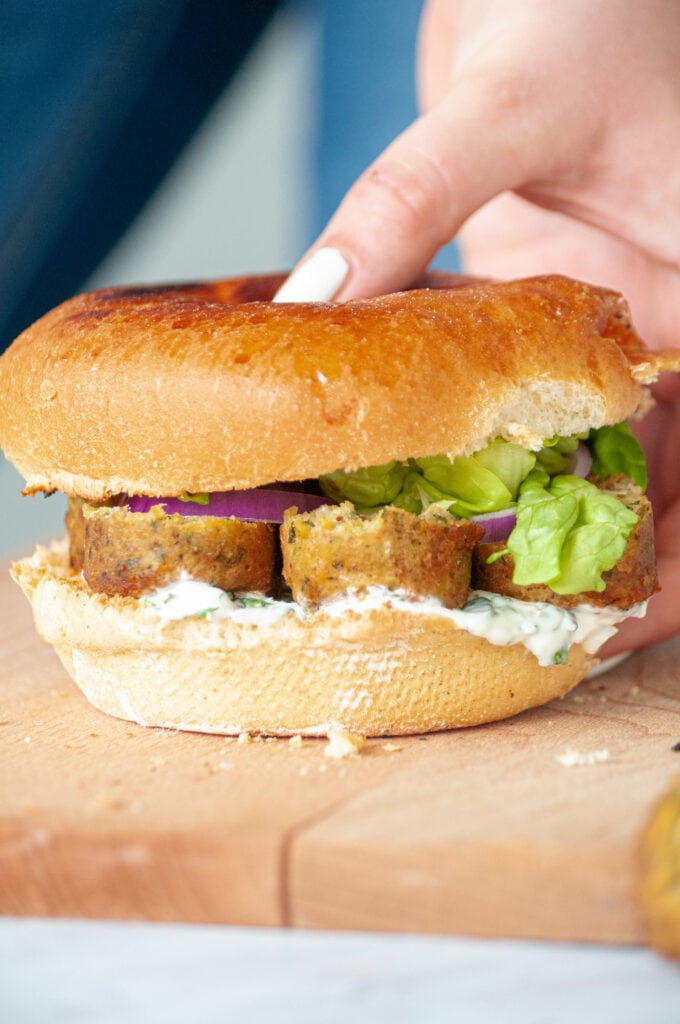 Falafel burger sur une planche pris par une main.