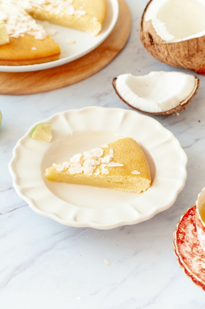 Part de gâteau exotique dans une assiette, avec le gâteau entier derrière.