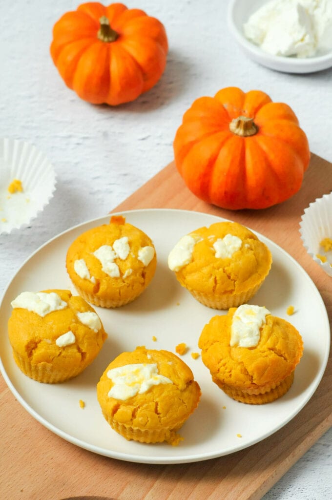 Muffins potiron et chèvre dans une assiette avec des mini citrouilles et du chèvre.
