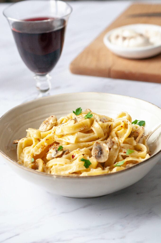 Pasta with Gorgonzola cream in a bowl with a glass of red wine.