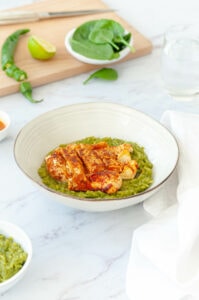Riz poblano et poulet aux épices dans une assiette avec planche à découper et légumes derrière.