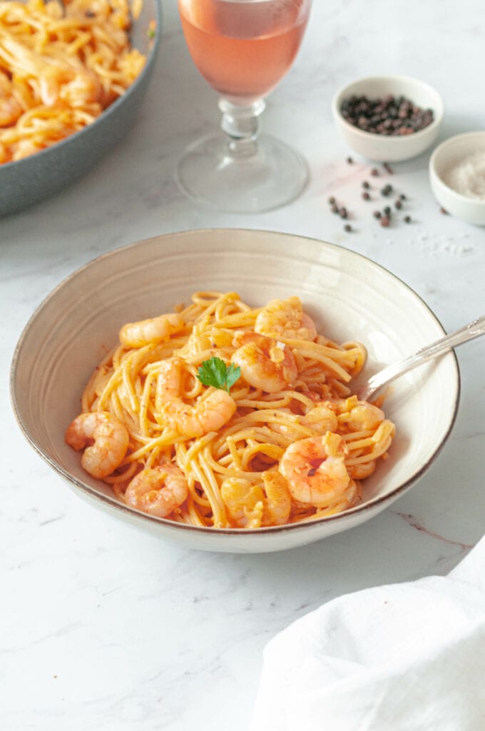 Spaghetti dans un bol avec un verre de rosé et deux petites soucoupes de sel et de poivre.