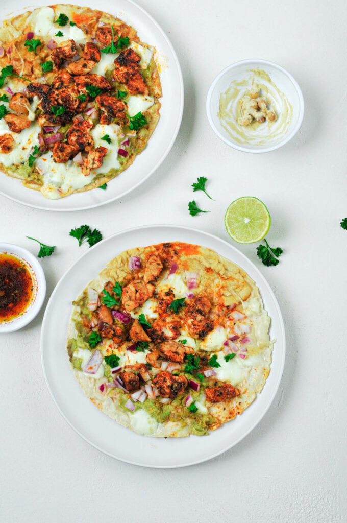 Deux tacos houmous, guacamole et poulet mariné dans deux assiettes.