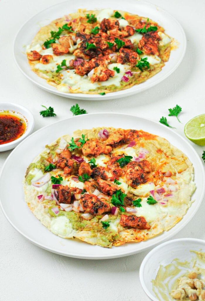 Deux tacos houmous, guacamole et poulet mariné dans deux assiettes.