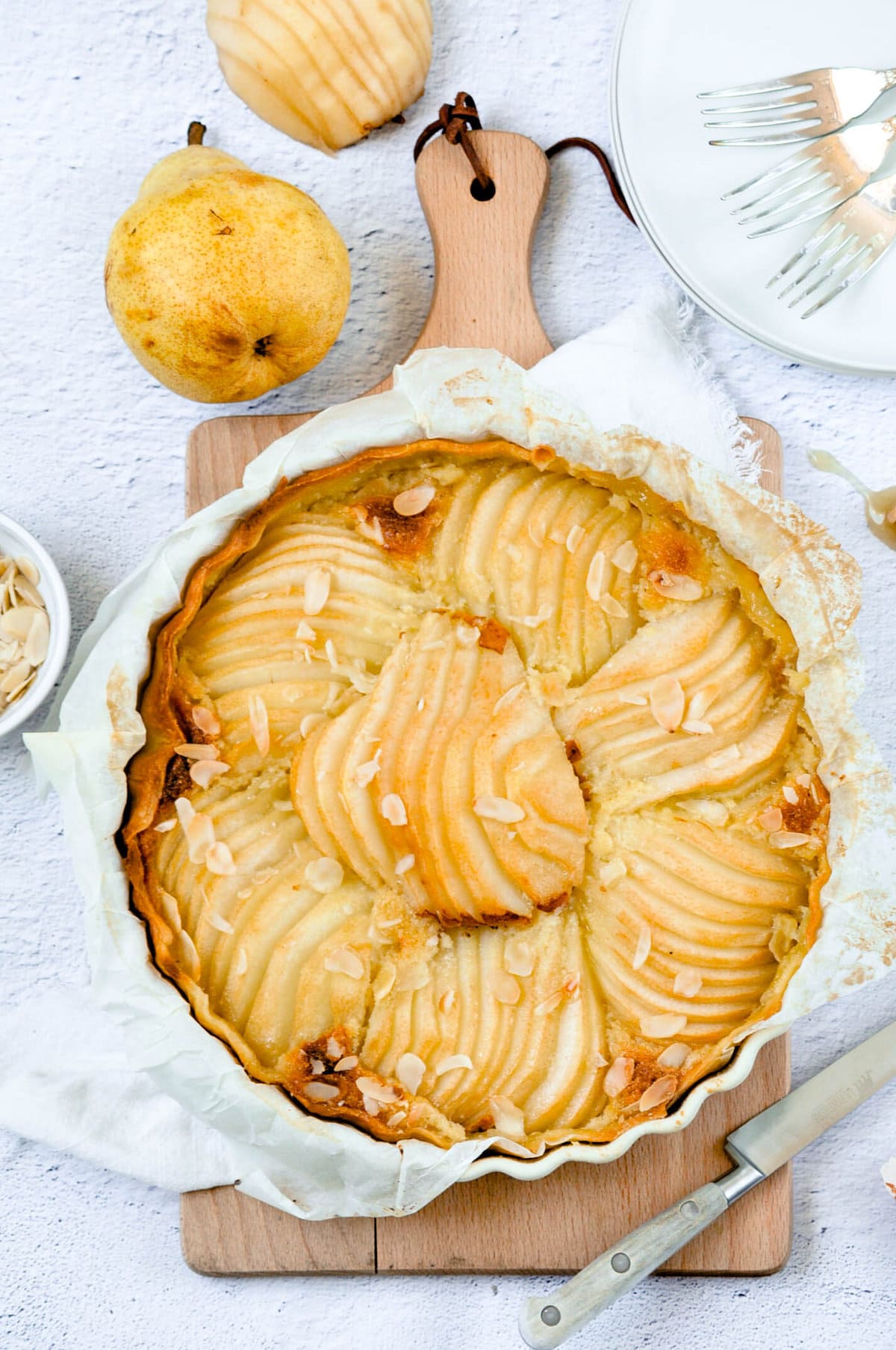 Pear tart on a board with several pears.