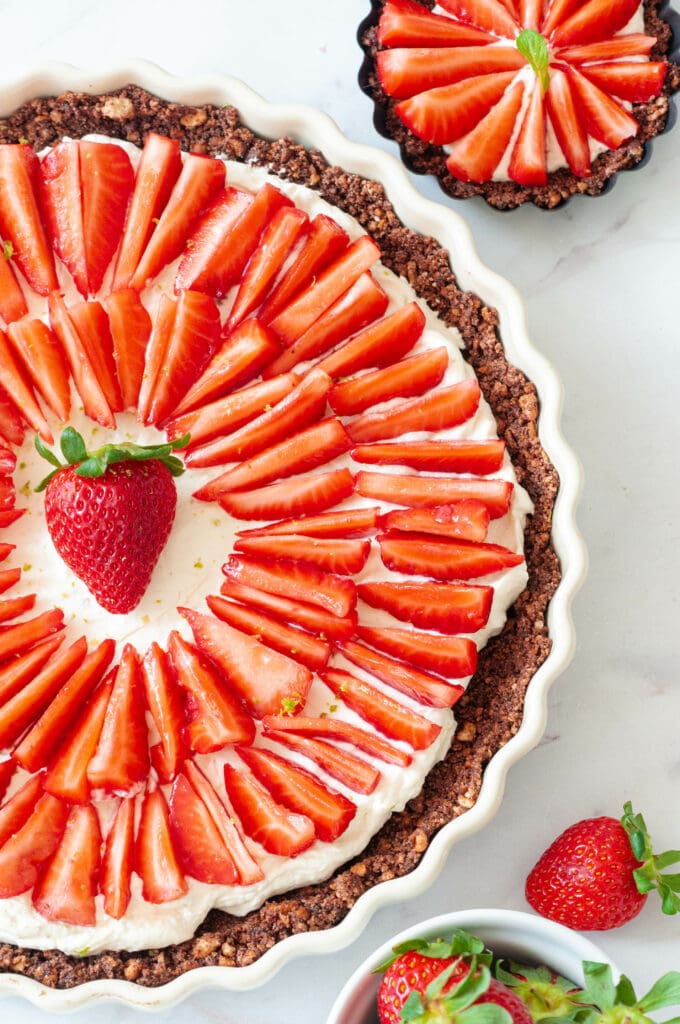 Zoom sur cette tarte sans cuisson avec des tartelettes et des fraises.