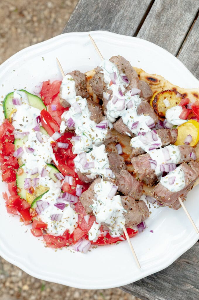 Souvlaki-style pork kebabs with grilled vegetables, yogurt sauce and pita