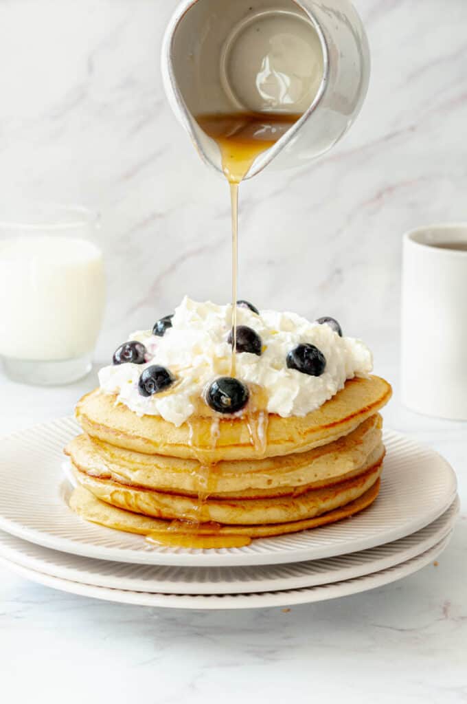 Pile into pancakes on a plate with whipped cream and a jug of maple syrup.