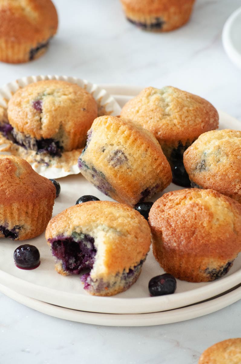 Blueberry muffins on a plate with a crunchy muffin.