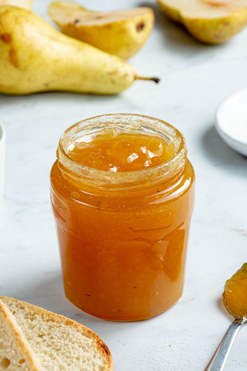 Pear jam with slices of bread and several pears.