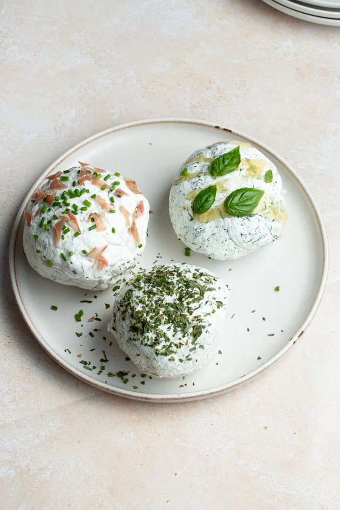 3 boules de Labneh dans une assiette blanche, avec des goûts et des toppings différents.