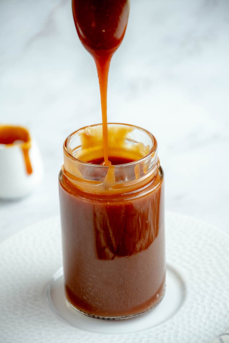 Salted butter caramel in a jar with a spoon to scoop it up.