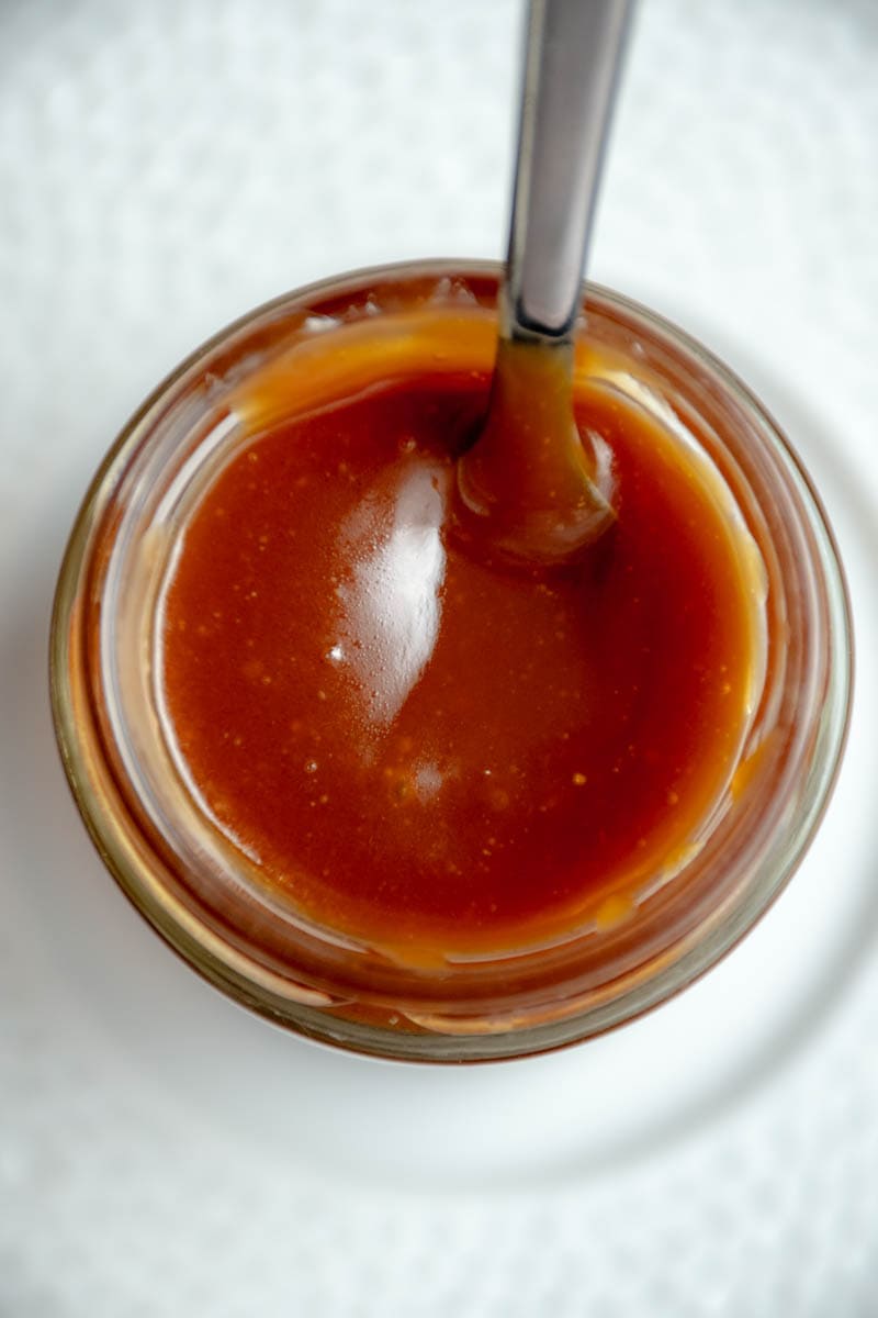 Caramel beurre salé in a jar with a spoon.