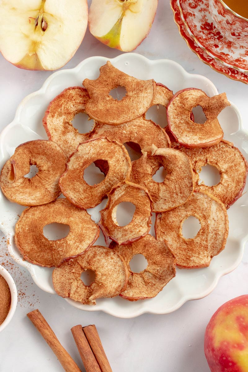 Apple chips on a plate with a cup of tea.