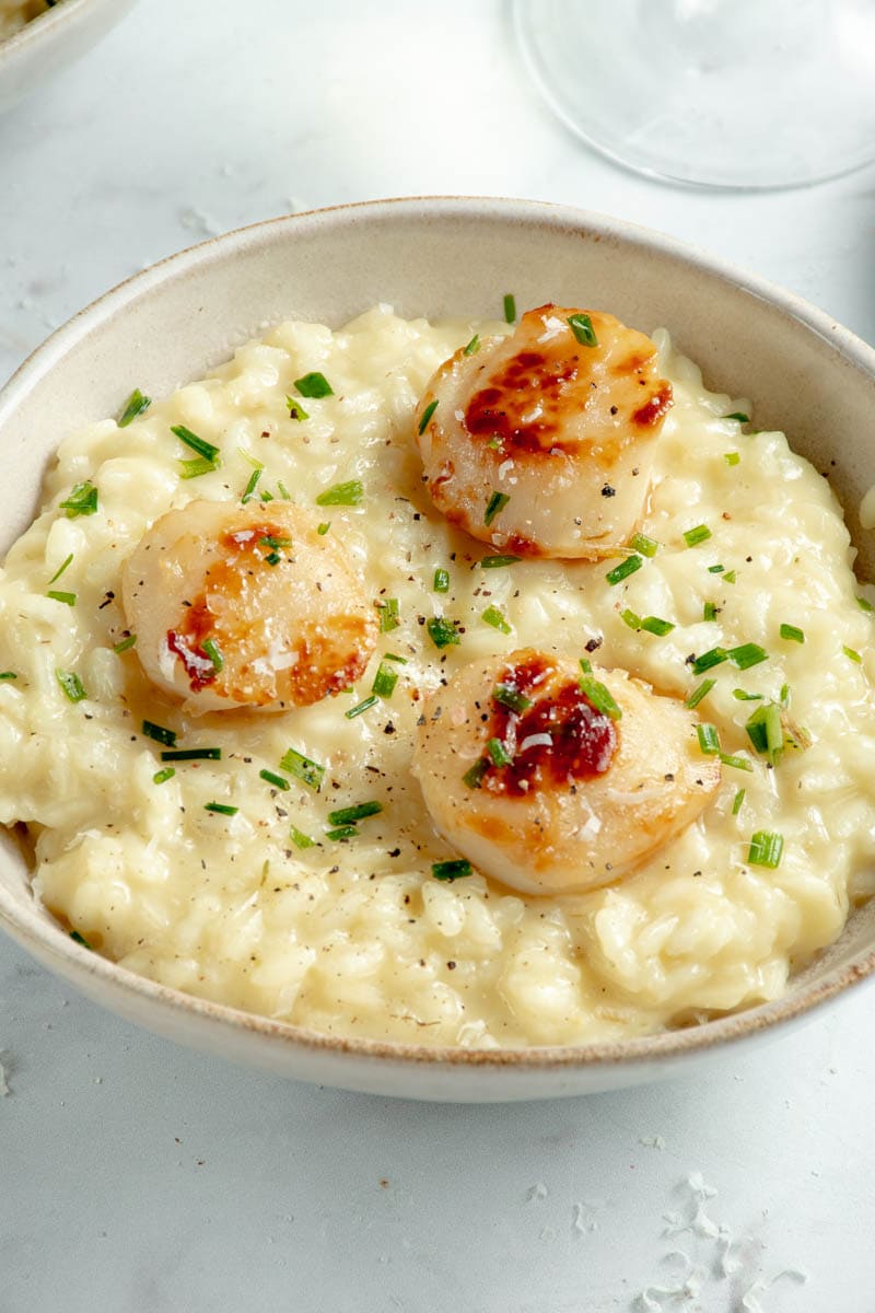 Scallop risotto with a glass of white wine and a napkin.