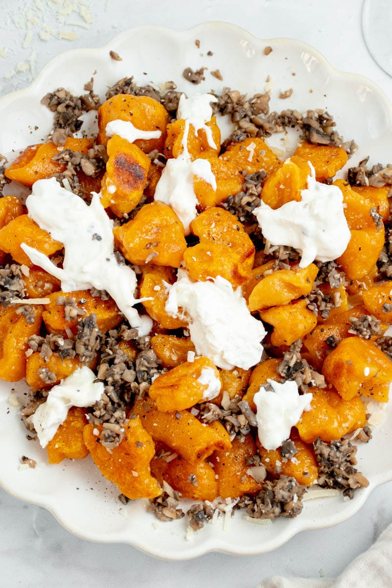 Sweet potato gnocchi on a plate with burrata and mushrooms.