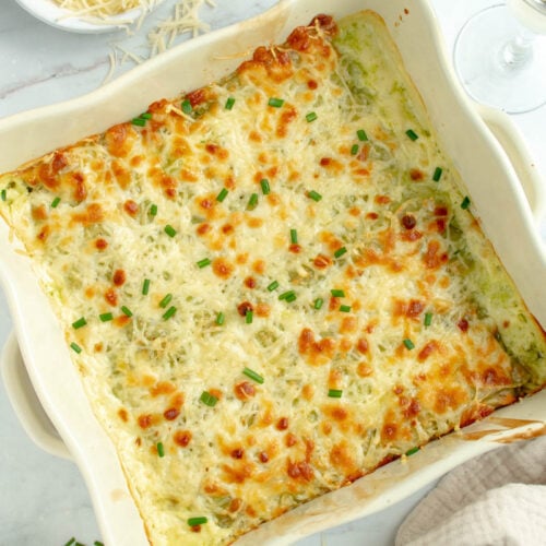 Gratin de ravioles dans un plat avec un bol de fromage râpé.