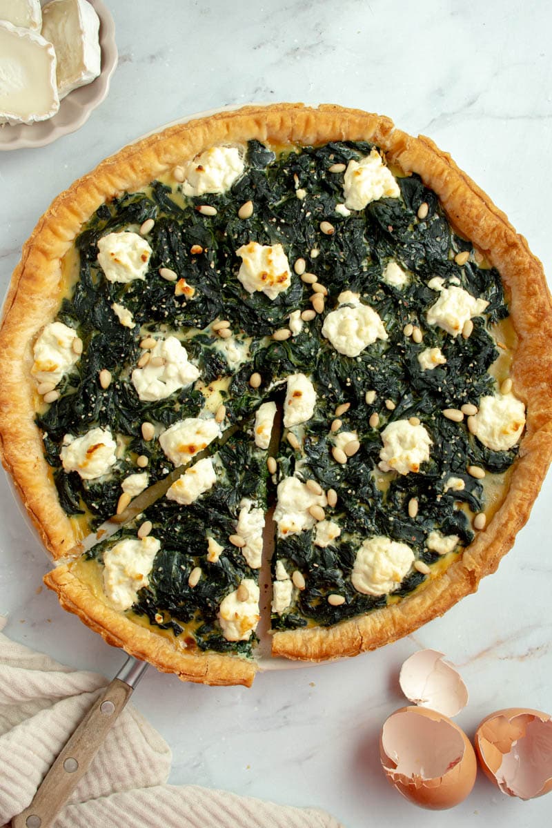 Spinach pie with a scoop that takes a slice.