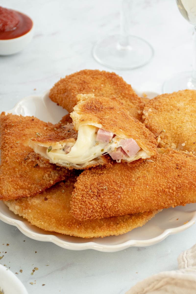 Sofficini coupé en deux, avec du fromage et du jambon dégoulinant.