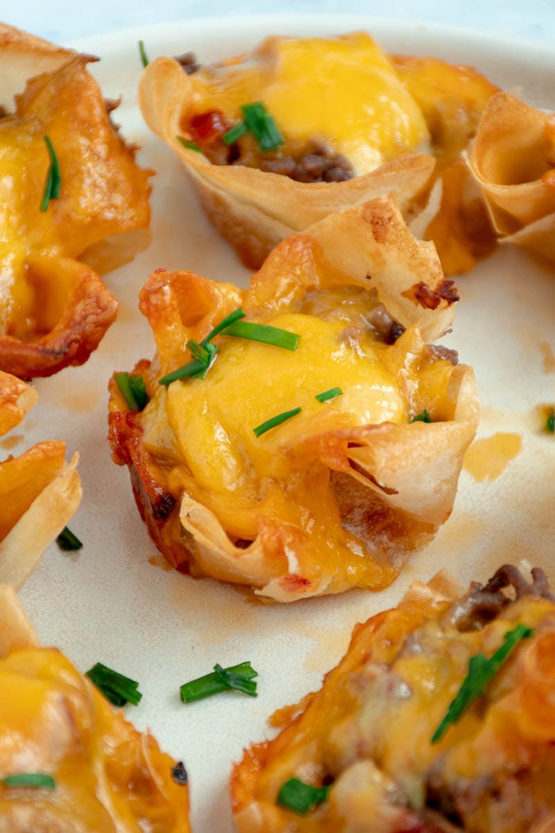 Burger-style appetizer bites on a plate with chives.