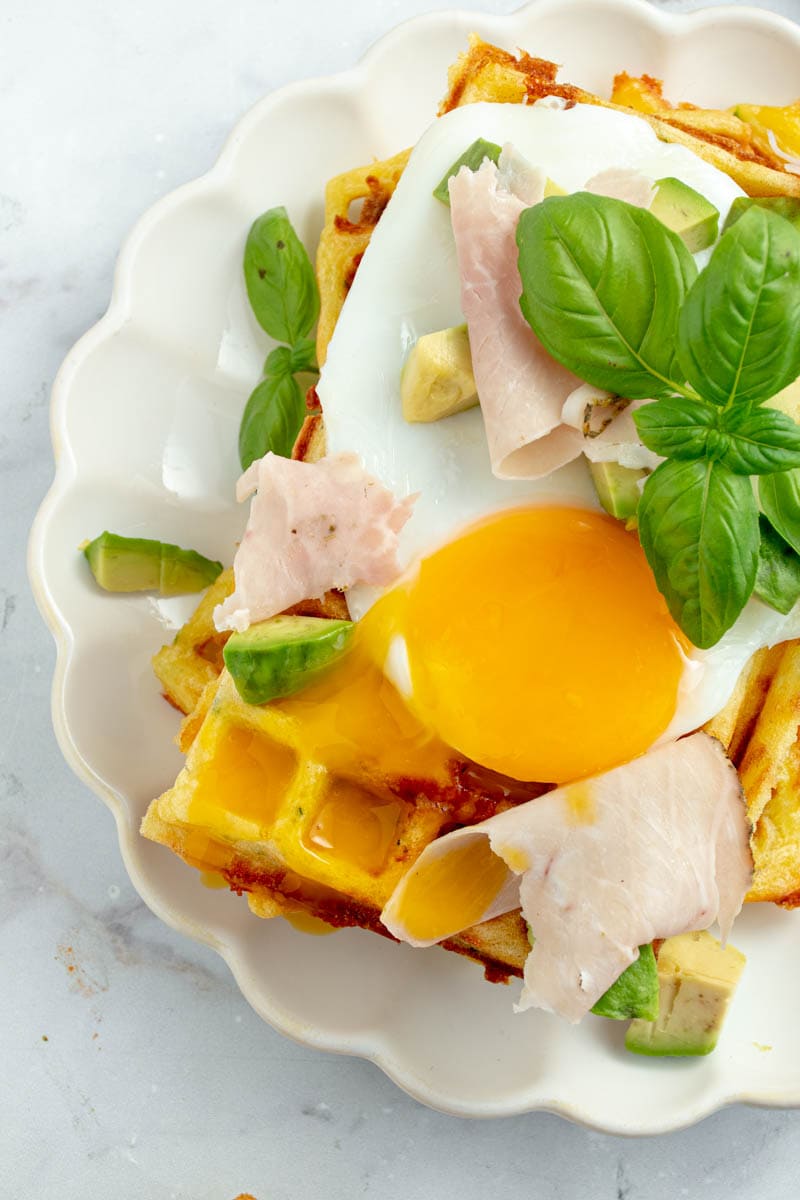 Zucchini and cheddar waffle with fried egg, basil and ham.