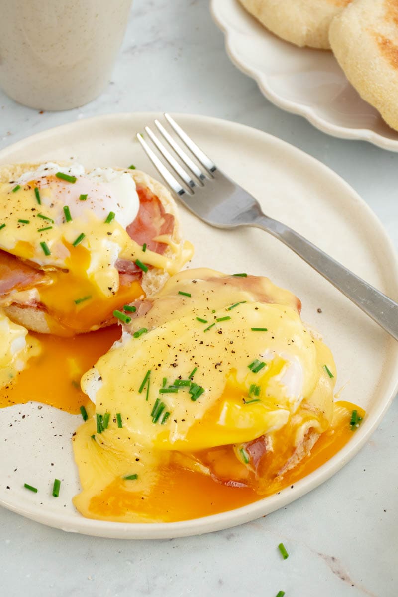 Eggs Benedict on a plate with a fork.