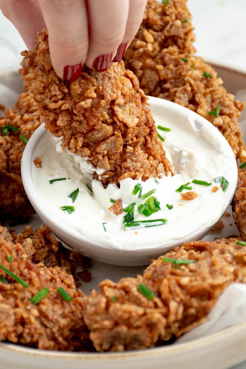 Homemade tenders in a bowl with a small saucer of white sauce.