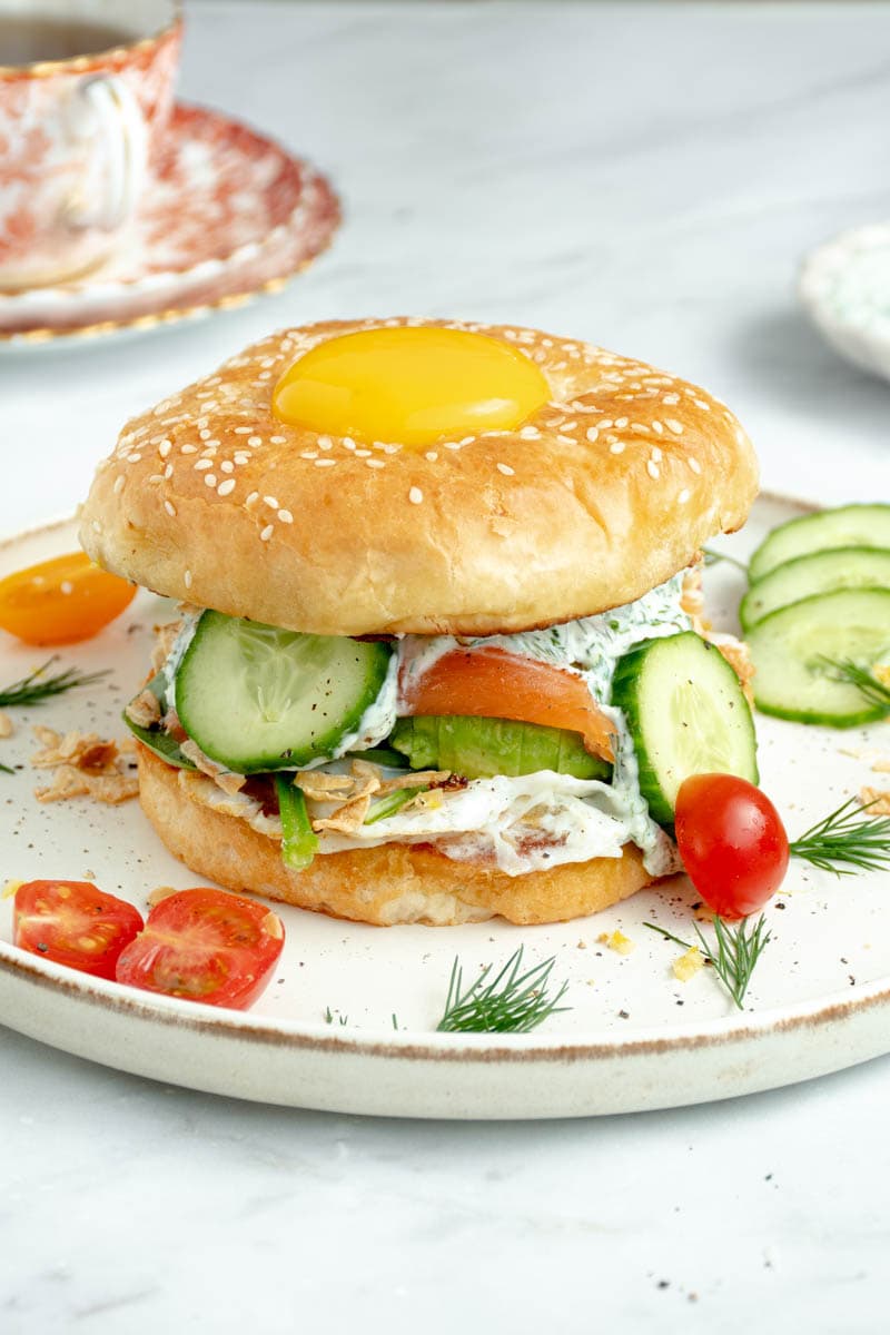Salmon bagel on a plate with a runny egg on the top cap.