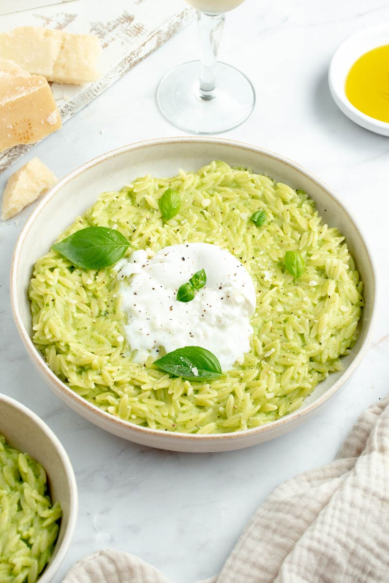 Orzo with zucchini cream on a plate with burrata and basil.